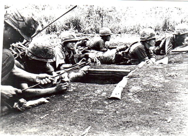 A group of soldiers sitting in the dirt.